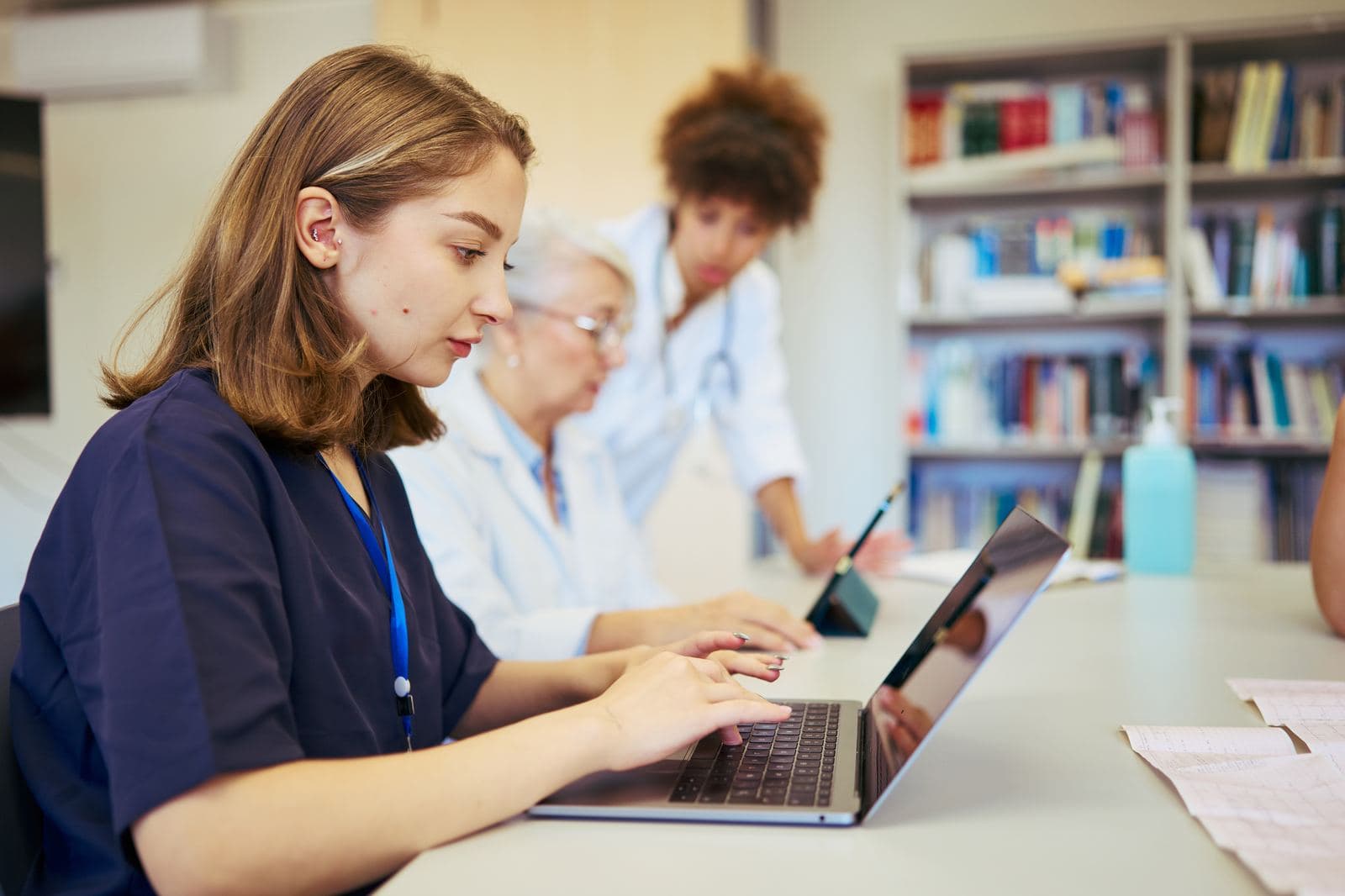 What Sets Us Apart Nurse typing on a laptop while doctors collaborate, representing the hospice and palliative care certification team